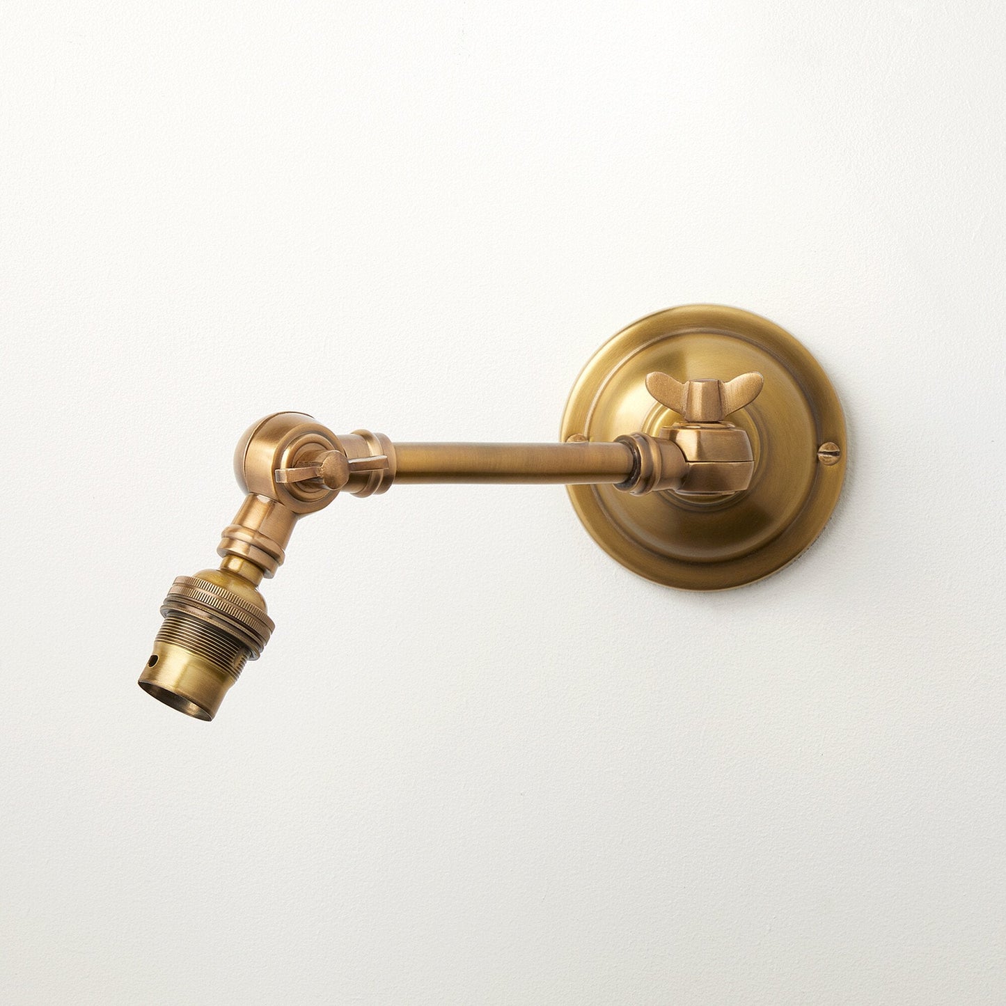 Double jointed wall fitting in antiqued brass