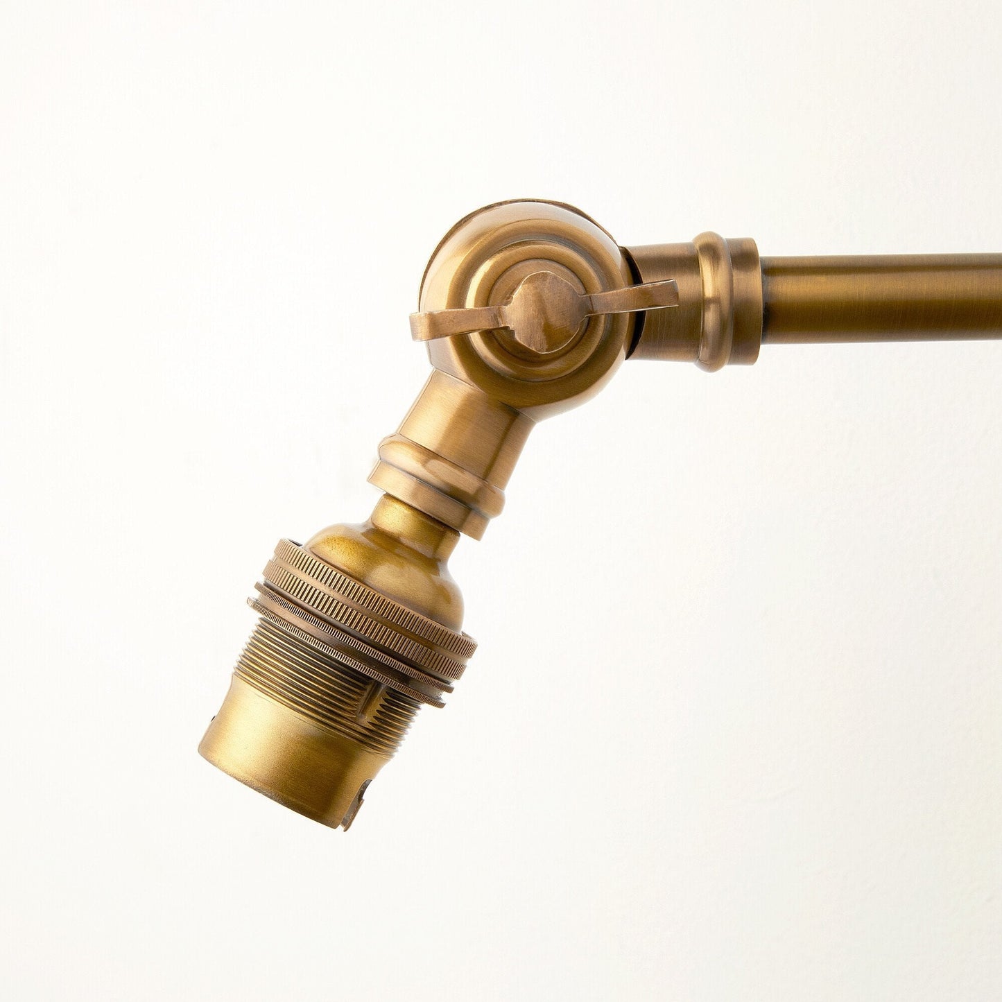 Double jointed wall fitting in antiqued brass